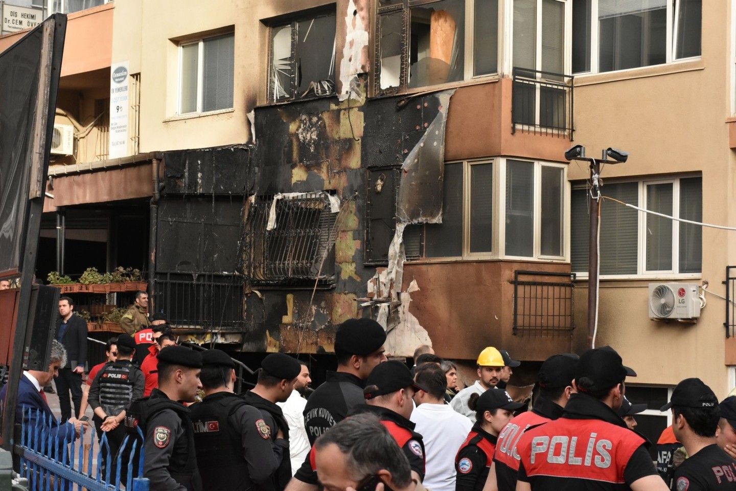 Einsatzkräfte stehen nach einem Brandausbruch vor einem teilweise verbrannten Gebäude.